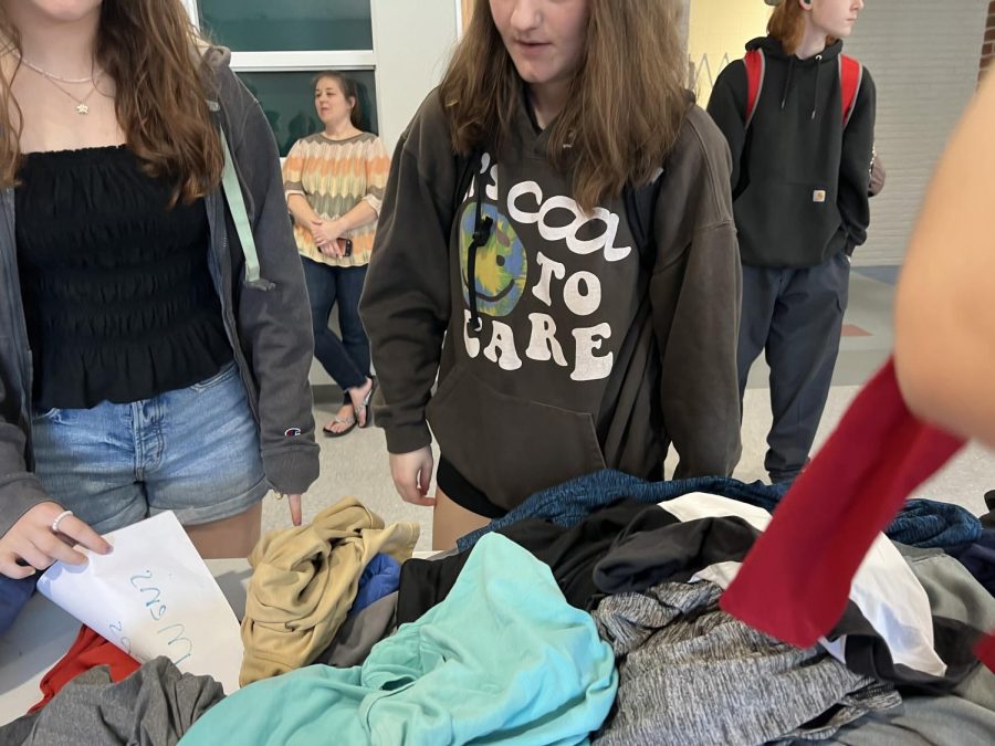 A+group+of+students+look+through+a+pile+of+shirts+at+the+CHS+Sustainable+Thrift+Shops+most+recent+event+on+Main+Street.+All+clothing+is+available+for+free.+One+of+the+organizers%2C+reading+teacher+Jen+Speidel%2C+can+be+glimpsed+here+in+the+background.